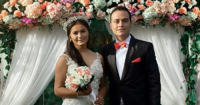Bride and groom under a floral wedding backdrop