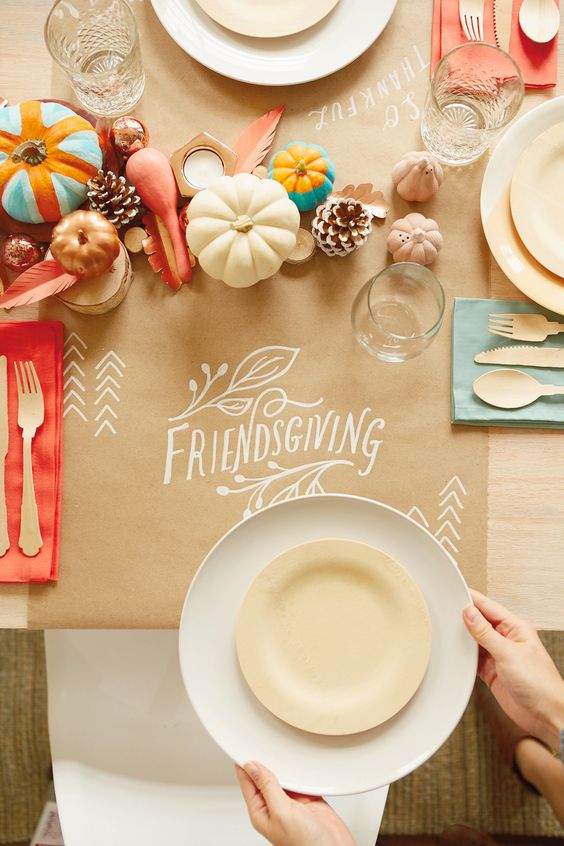 Friendsgiving place setting with pumpkins and pinecones