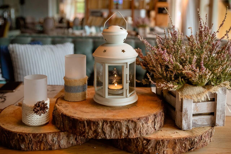 Lantern and candles on wooden slices with dried flowers