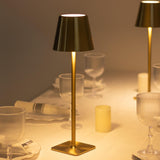 Elegant gold table lamp illuminating a dining setting with glasses and candles.
