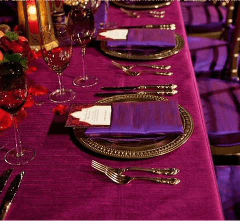 Purple banquet table set with gold charger plates and glassware