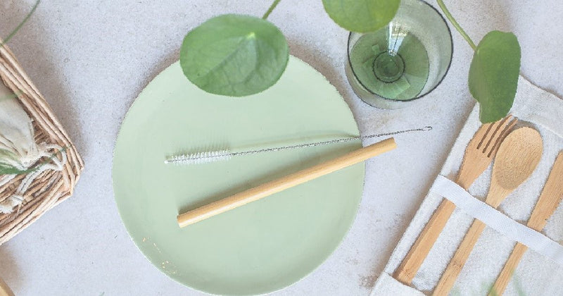Mint green plate with bamboo utensils and a glass