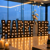 Illuminated marquee letters spelling “MARRY ME” at a romantic engagement proposal venue