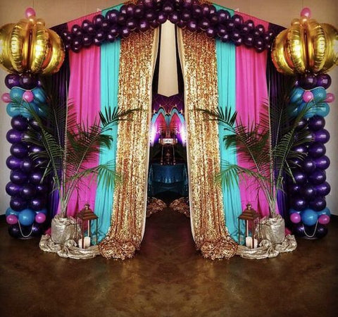 Balloon arch with gold sequin drapes and palm accents