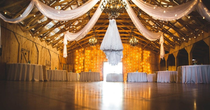 Barn wedding reception with draped white fabric and lights