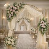 Elegant wedding arch adorned with roses and greenery in a romantic venue setting.
