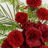 Red artificial flowers bouquet with greenery accents.