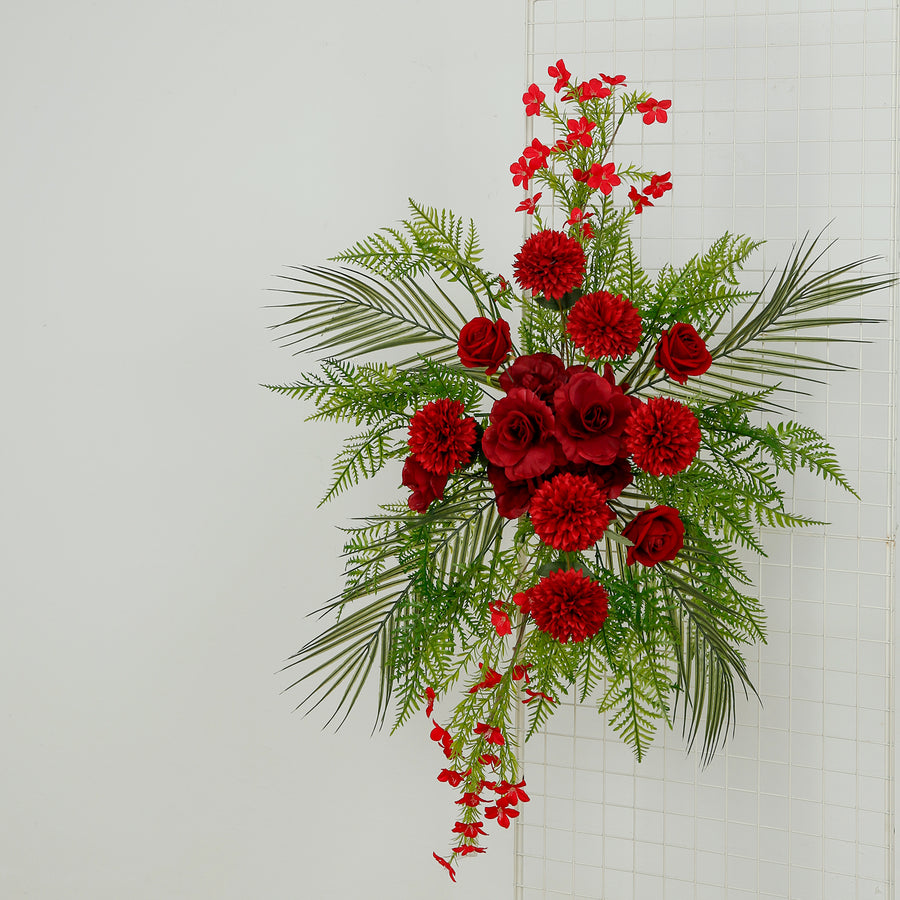 Red floral arrangement with roses and greenery on a white background.