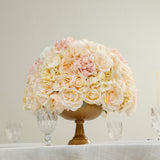 Floral arrangement in a gold vase with soft pink and cream roses.