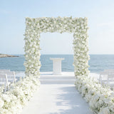 Elegant floral wedding arch by the sea with white flowers and chairs.