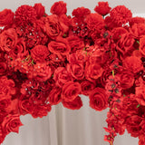 Red floral arrangement with roses and carnations on a white backdrop