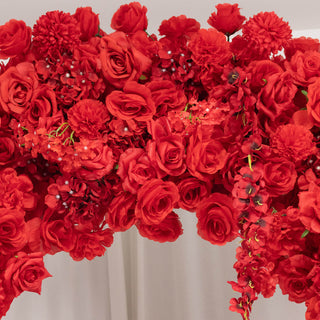 Red floral arrangement with roses and carnations on a white backdrop