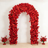 Red floral arch with rose arrangements and bouquets on a white wall background