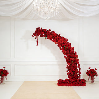 Elegant floral arch made of red roses with matching floral arrangements.