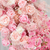Pink floral arrangement with roses and orchids in various shades.