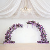 Purple floral arrangement arch with roses and flowers in a staged setting.