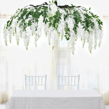 Floral chandelier with white flowers and greenery above a dining table setting.