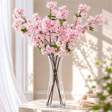 Pink cherry blossom arrangement in a clear glass vase in a bright room
