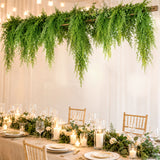 Elegant wedding table with candles, greenery, and hanging fern decor