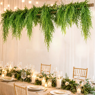 Elegant wedding table with candles, greenery, and hanging fern decor