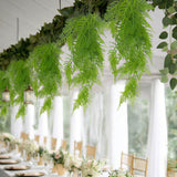 Elegant wedding reception table with hanging green ferns and white drapery
