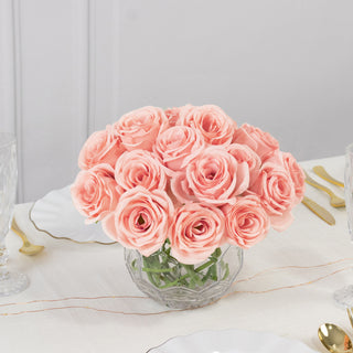 Pink roses in a crystal vase on a dining table setting.