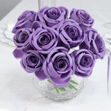 Purple roses bouquet in a clear vase on a table.