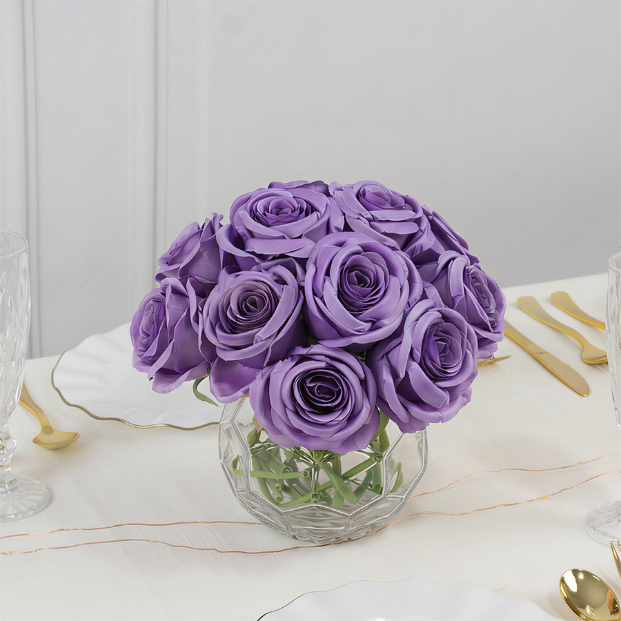 Purple rose bouquet in a clear vase on a table setting.