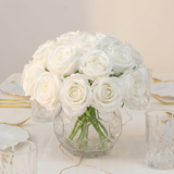 White roses bouquet in a clear vase on a table setting.
