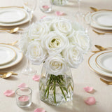 White rose bouquet in a glass vase on a dining table with elegant tableware.