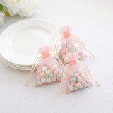 Pastel candy gift bags beside white plates on a soft white tablecloth