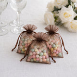 Chocolate organza favor bags filled with pastel candy balls on a white table