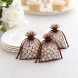 Pastel candy favor bags in brown organza on a white table setting