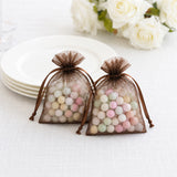 Brown organza gift bags with pastel candy balls on a white table