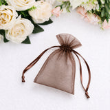 Brown sheer organza gift pouch with ribbon ties on white floral background