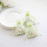 Pastel candy favor bags beside white plates on a white tablecloth
