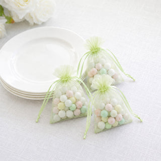 Pastel candy favor bags beside white plates on a white tablecloth