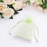 Sheer green organza gift pouch with floral arrangement background