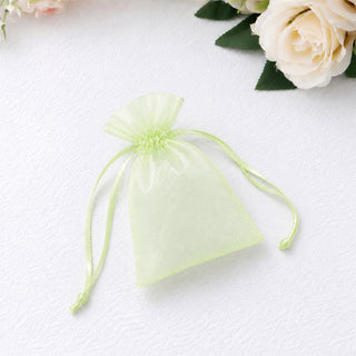 Light green organza drawstring gift pouch on white textured background