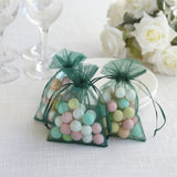 Colorful decorative candy bags in green mesh on a table with white roses.