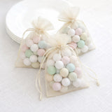 Pastel-colored candy bags tied with ribbon, arranged on a light background.