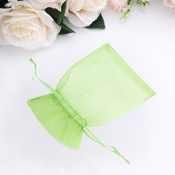 Green organza gift bag with drawstring closure on a plain background