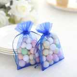 Two blue organza bags filled with pastel-colored candies.