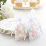 Pastel candy in sheer organza gift bags on white plates