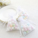 Pastel candy in sheer organza gift bags on a white plate