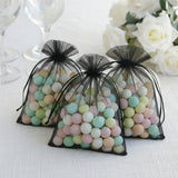 Three black organza bags filled with pastel-colored candy pearls.