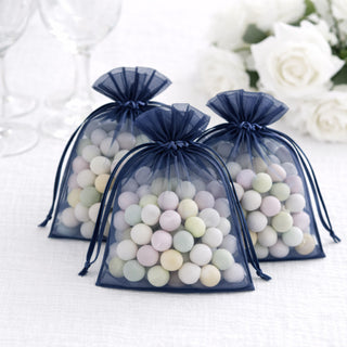 Three navy organza bags filled with pastel-colored candies on a white background.