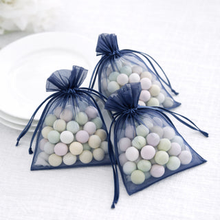 Three navy organza bags filled with pastel-colored decorative stones.