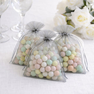 Pastel candy-filled bags on a table with a floral arrangement.