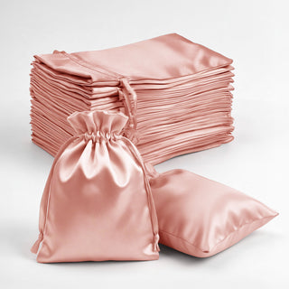 Satin drawstring bags in soft pink, stacked and one bag on the side.